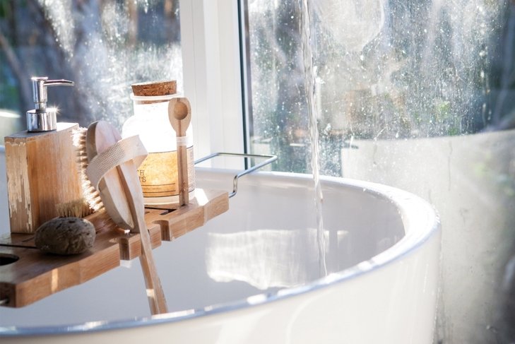 hydrated sink in a bathroom with many facial cleansers and soaps.