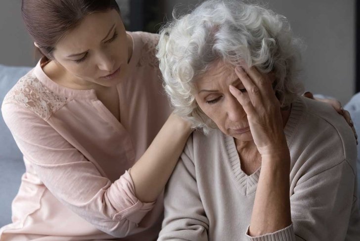 Close up loving daughter hugging, comforting frustrated mature mother, helping to overcome problems, unhappy senior female touching forehead, suffering from headache, feeling unwell