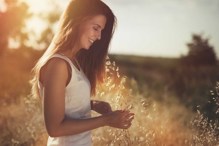 Beautiful carefree woman in fields being happy outdoors