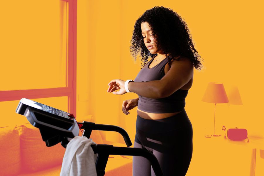 Woman looking at smart watch on the treadmill at home