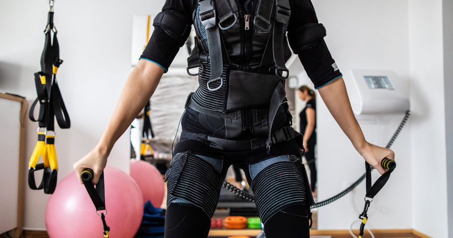 ems workout: woman using arm bands while strapped into an electrical muscle stimulation (ems) machine