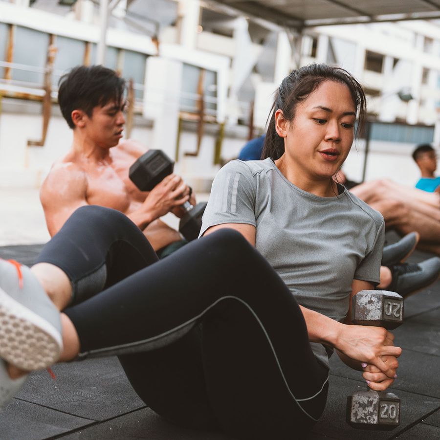 ab workout with weights female: woman doing core abs workout with weights, specifically a russian twist with a 20 pound dumbbell